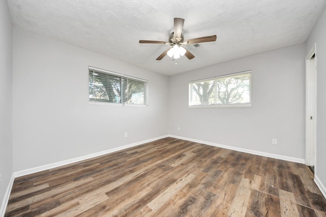 empty room featuring a textured ceiling, ceiling fan, dark hardwood / wood-style flooring, and plenty of natural light