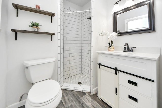 bathroom featuring tiled shower, vanity, and toilet