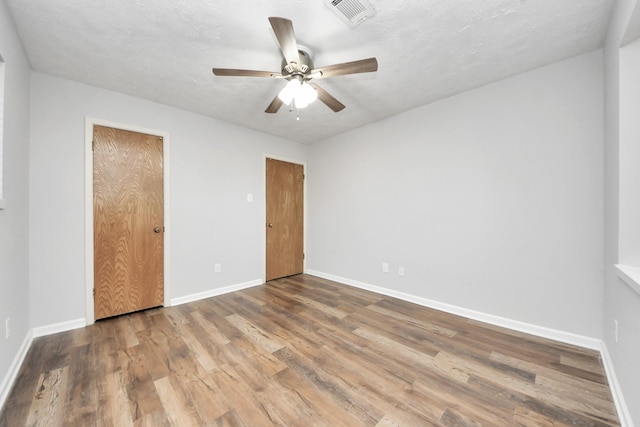 unfurnished bedroom featuring ceiling fan, hardwood / wood-style floors, and a textured ceiling