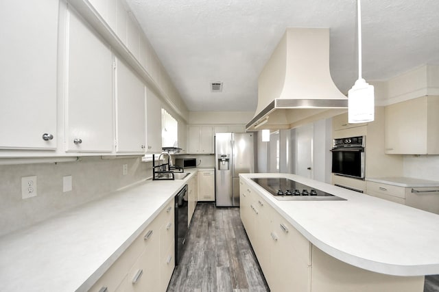 kitchen with sink, hanging light fixtures, white cabinets, black appliances, and custom range hood