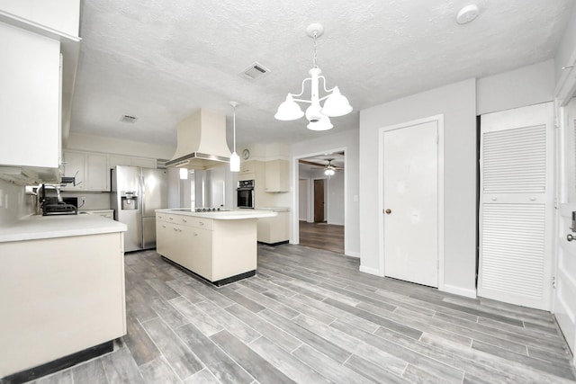 kitchen featuring a center island, black appliances, decorative light fixtures, white cabinetry, and custom range hood