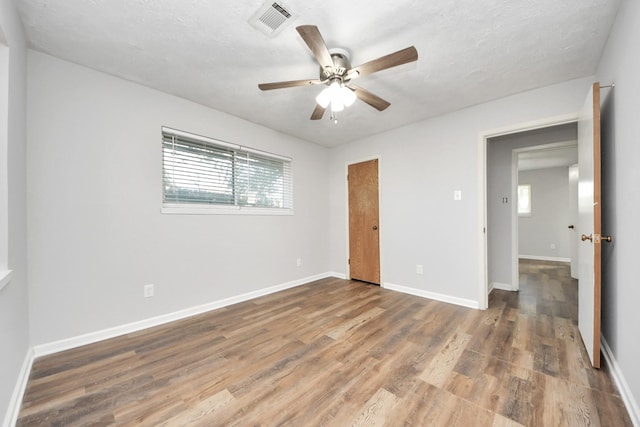 unfurnished bedroom featuring ceiling fan, hardwood / wood-style floors, and a textured ceiling