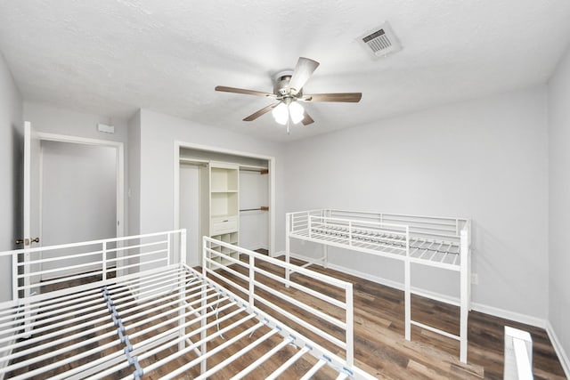 unfurnished bedroom with a textured ceiling, hardwood / wood-style flooring, a closet, and ceiling fan