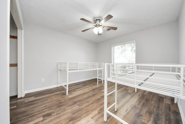 unfurnished bedroom featuring ceiling fan and dark hardwood / wood-style floors