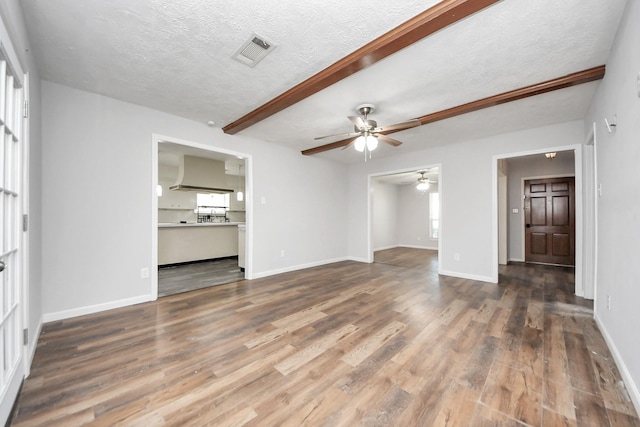 unfurnished living room featuring beam ceiling, a textured ceiling, dark hardwood / wood-style flooring, and ceiling fan