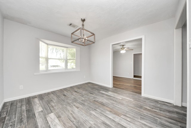 unfurnished room featuring a textured ceiling, dark hardwood / wood-style floors, and ceiling fan with notable chandelier