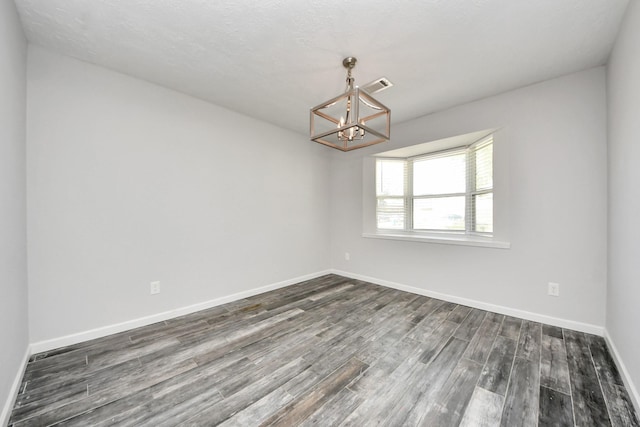 unfurnished room featuring dark hardwood / wood-style flooring and an inviting chandelier