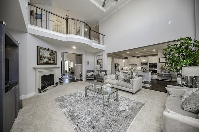 living room featuring carpet flooring, crown molding, and a high ceiling