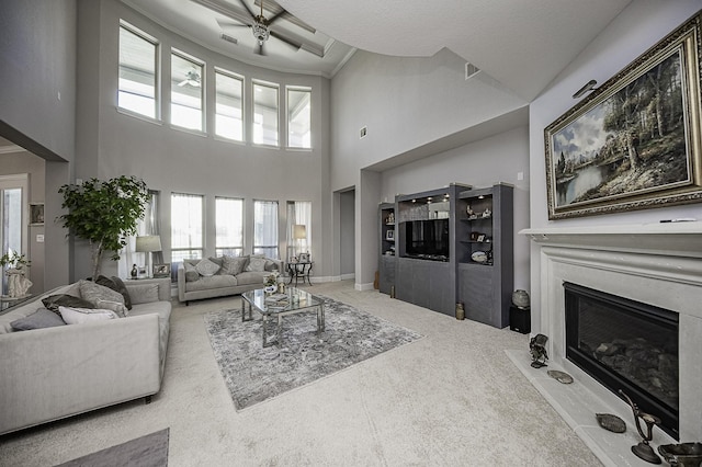 living room with carpet floors, crown molding, a towering ceiling, and ceiling fan