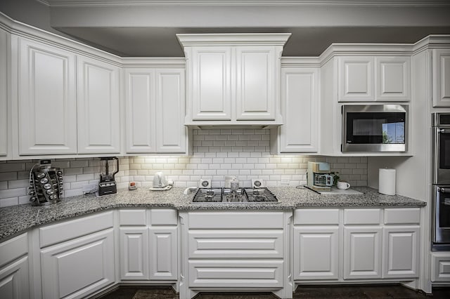 kitchen with tasteful backsplash, light stone countertops, white cabinets, and appliances with stainless steel finishes