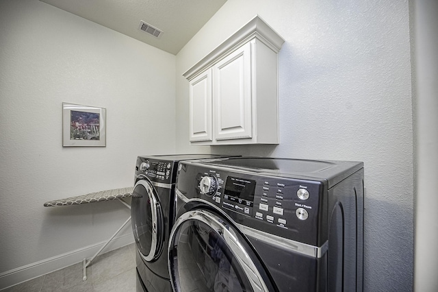 laundry room featuring cabinets, light tile patterned floors, and washing machine and dryer