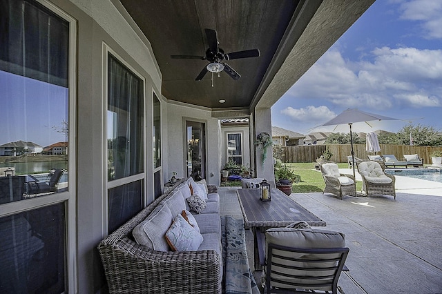 view of patio / terrace featuring a water view, ceiling fan, and a fenced in pool