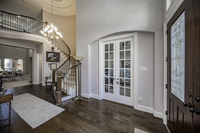 entryway with a chandelier, dark hardwood / wood-style flooring, a towering ceiling, and french doors