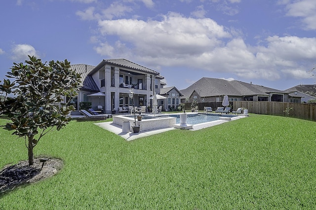 rear view of house featuring a lawn, a pool with hot tub, a balcony, and a patio