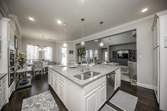 kitchen featuring dark wood-type flooring, white cabinets, sink, hanging light fixtures, and an island with sink