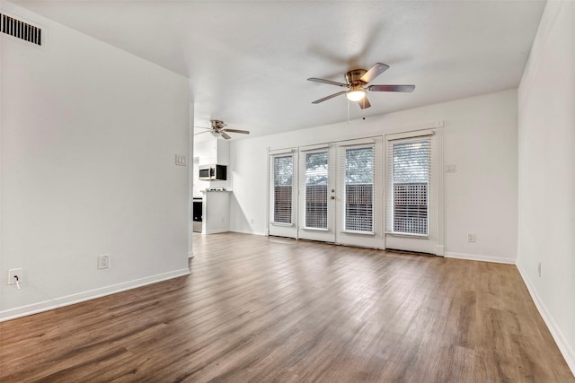 unfurnished living room featuring hardwood / wood-style floors, ceiling fan, and french doors