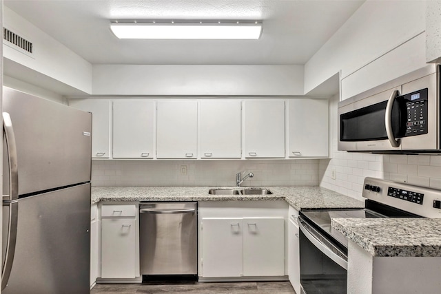 kitchen featuring white cabinets, light stone counters, sink, and appliances with stainless steel finishes