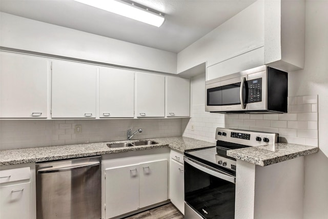 kitchen featuring white cabinets, sink, light hardwood / wood-style flooring, decorative backsplash, and appliances with stainless steel finishes