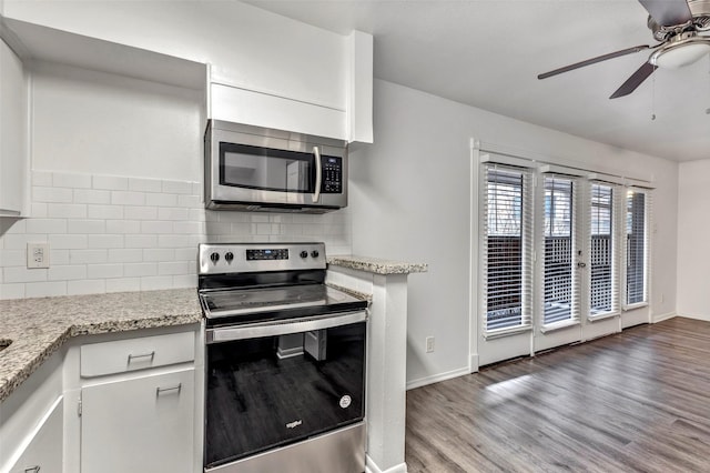 kitchen featuring decorative backsplash, light wood-type flooring, light stone counters, white cabinetry, and stainless steel appliances