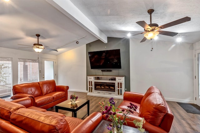 living room featuring vaulted ceiling with beams, rail lighting, wood-type flooring, and a textured ceiling