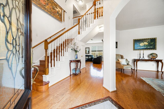 entryway with ornamental molding and wood-type flooring