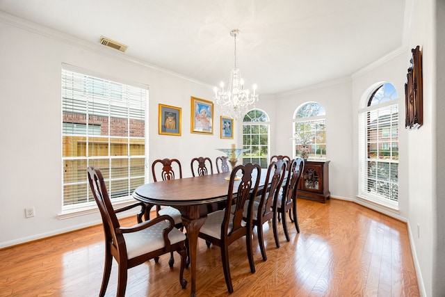 dining area with light hardwood / wood-style flooring, a wealth of natural light, ornamental molding, and a chandelier