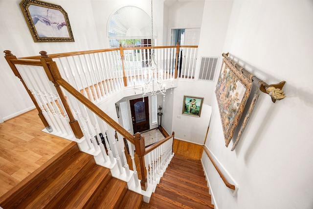 staircase with hardwood / wood-style flooring and a high ceiling