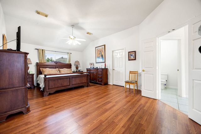 bedroom featuring hardwood / wood-style flooring, ceiling fan, ensuite bathroom, and lofted ceiling