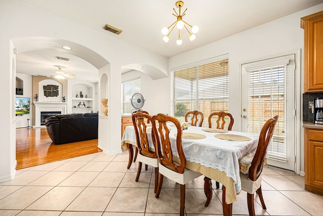 tiled dining area featuring ceiling fan with notable chandelier and built in features