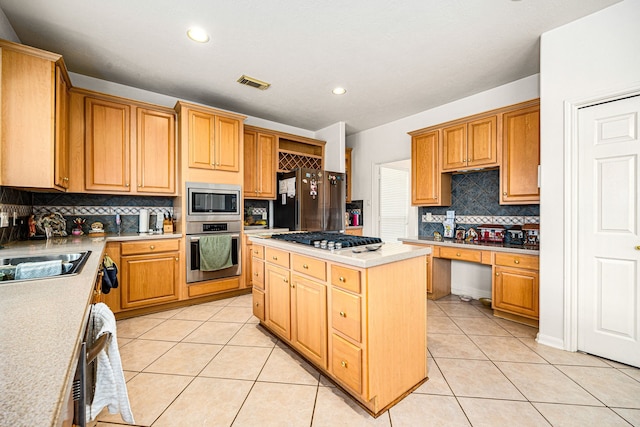 kitchen featuring light tile patterned floors, sink, stainless steel appliances, a center island, and tasteful backsplash