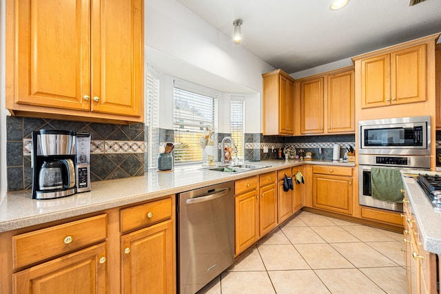 kitchen with light tile patterned floors, backsplash, sink, and appliances with stainless steel finishes