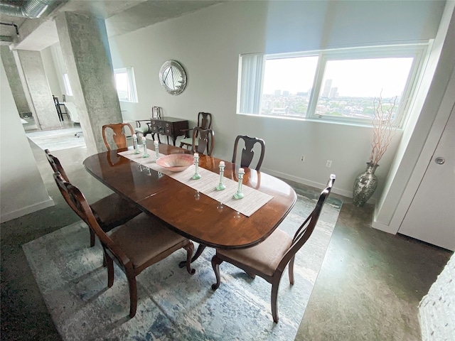 dining space with decorative columns and concrete floors