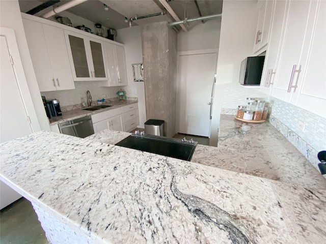 kitchen featuring kitchen peninsula, light stone countertops, stainless steel dishwasher, sink, and white cabinetry