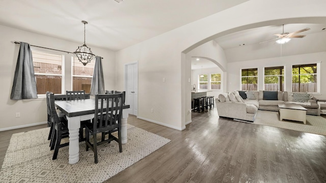 dining space featuring hardwood / wood-style floors, ceiling fan with notable chandelier, and lofted ceiling