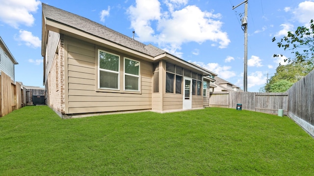 rear view of property featuring a lawn and central air condition unit