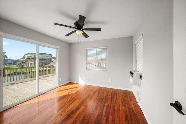 spare room with a water view, hardwood / wood-style flooring, and ceiling fan