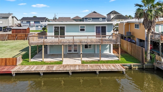 rear view of property featuring a patio area, a yard, and a deck with water view