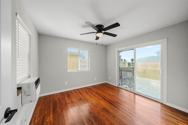 spare room with hardwood / wood-style floors, an AC wall unit, and ceiling fan