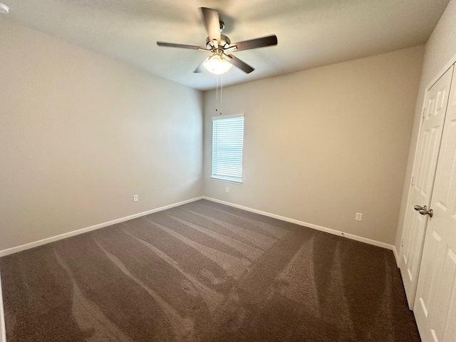 unfurnished bedroom with dark colored carpet and ceiling fan