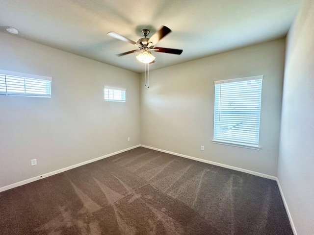 spare room featuring ceiling fan and dark carpet