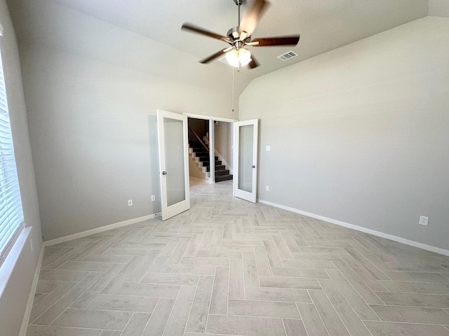 empty room with ceiling fan, lofted ceiling, light parquet flooring, and french doors