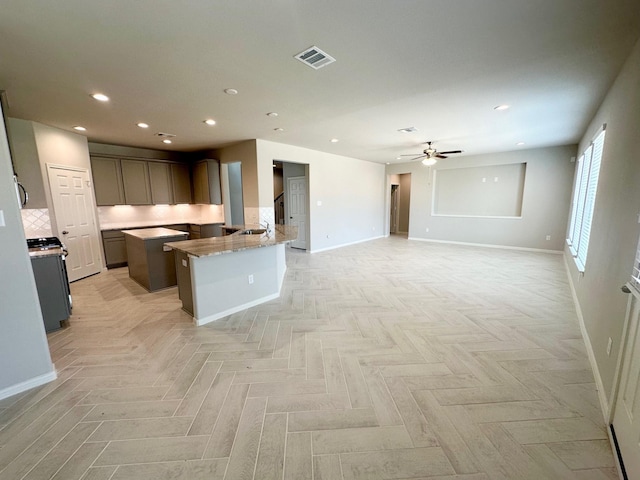 kitchen featuring gas stove, light stone countertops, light parquet floors, and ceiling fan