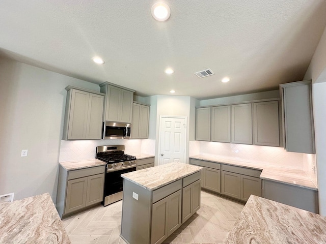 kitchen featuring light parquet flooring, stainless steel appliances, and gray cabinetry