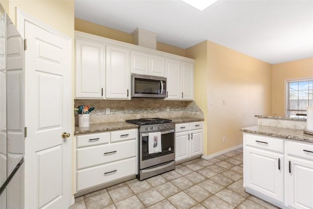 kitchen with tasteful backsplash, white cabinetry, light stone counters, and appliances with stainless steel finishes