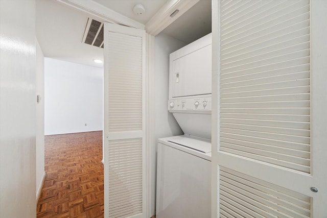 laundry area with parquet flooring and stacked washer and dryer