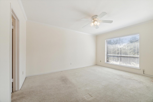 unfurnished room with ceiling fan, light colored carpet, and crown molding