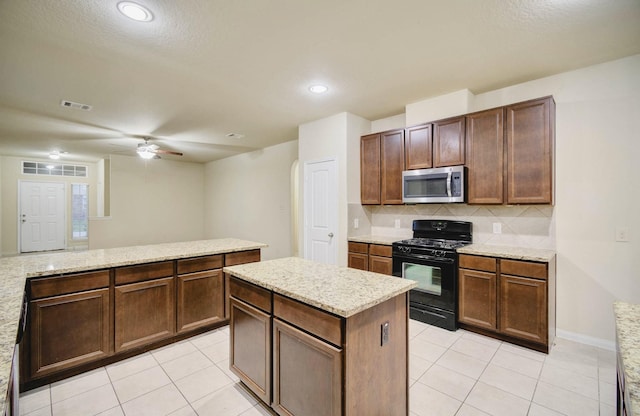 kitchen featuring light tile patterned floors, decorative backsplash, a kitchen island, black gas range, and ceiling fan