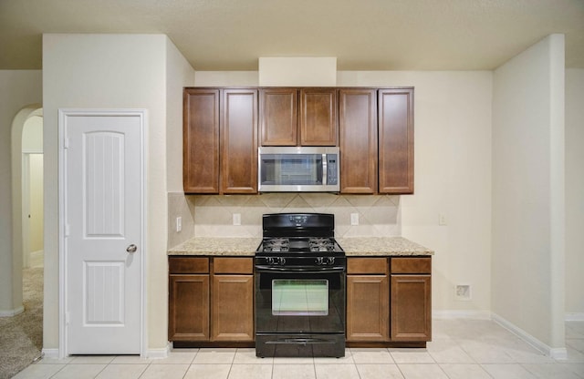 kitchen with decorative backsplash, black gas stove, and light tile patterned floors