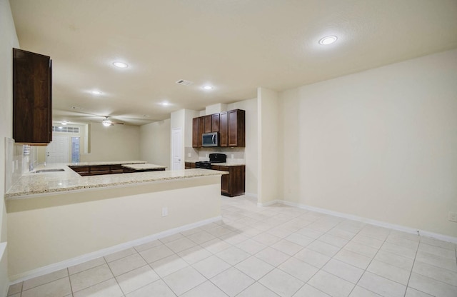 kitchen featuring light tile patterned floors, stove, sink, kitchen peninsula, and light stone counters