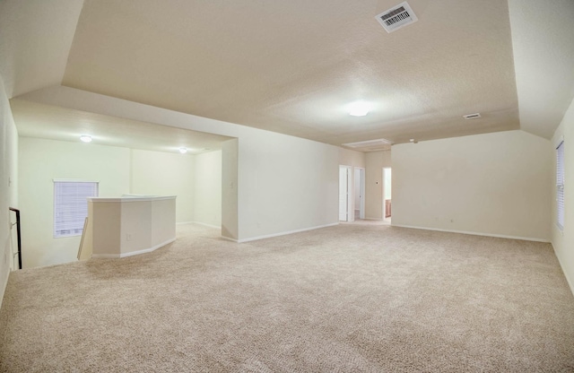 carpeted spare room with a textured ceiling and vaulted ceiling